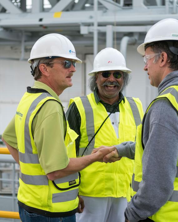 NFE employees standing together shaking hands